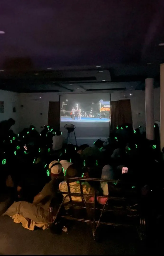 The audience in glowing headphones watching the film in the dark